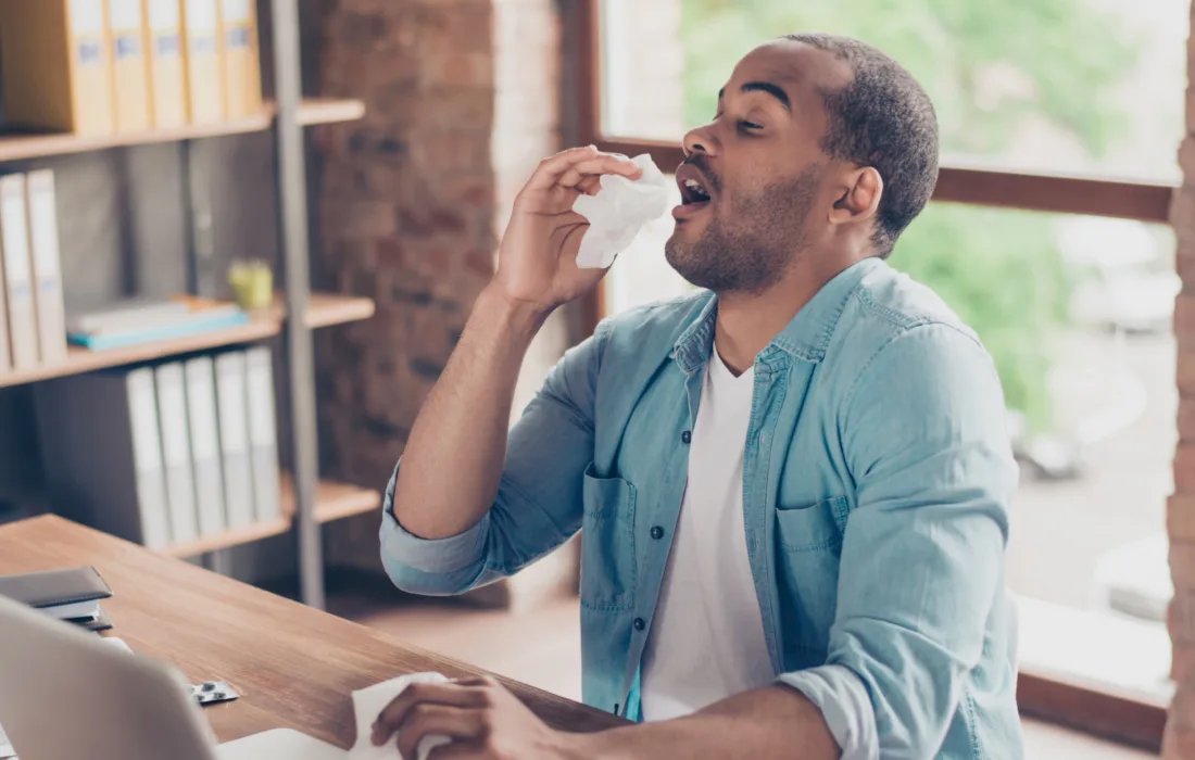 Man sneezing at a desk