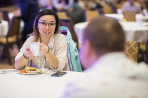 An ONPHA member sits with a cup of coffee, chatting with another ONPHA member across a table at the annual Conference.