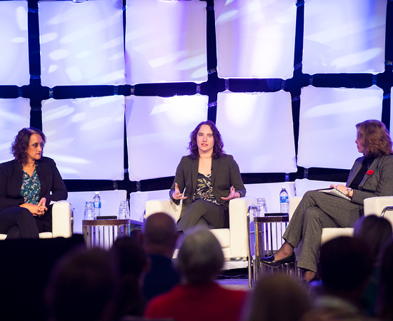 A panel of three women sits in discussion on a stage