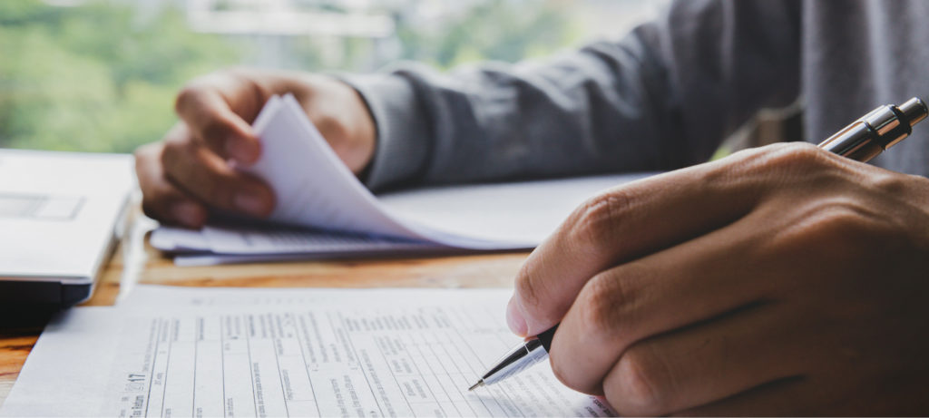 Close up of a man's hands as he works with tax forms