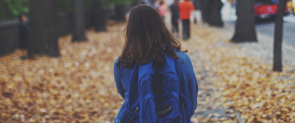 Young girl with a blue backpack walking to school
