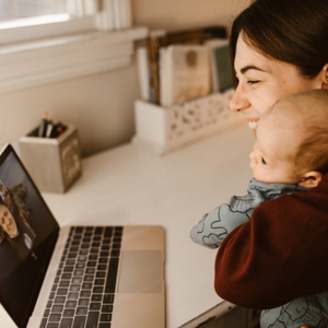 Woman chatting on zoom and holding a baby