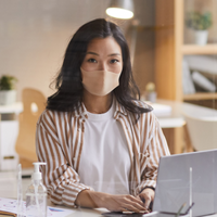 Woman wearing a face mask at desk with laptop