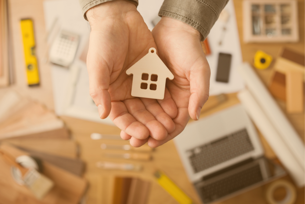 Woman's hands holding a small wooden house