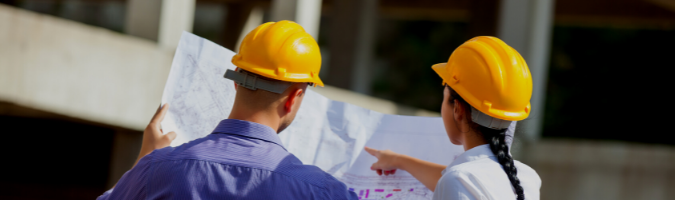 Two people discussing construction plans wearing yellow hard hats