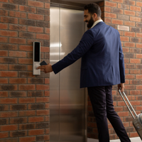 Business professional man holding a suitcase and pushing an elevator button