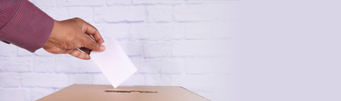 Hand placing a ballot in a ballot box