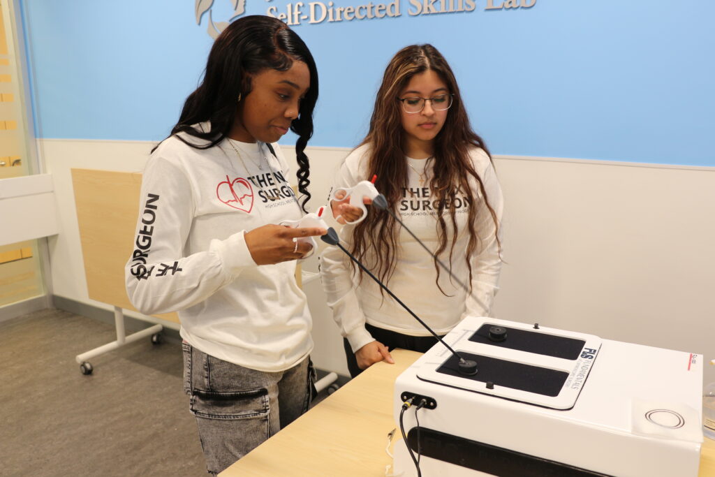 Two students using a robot to practice surgery skills